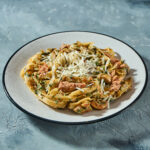 Italian pasta with seafood, canned tuna and parmesan cheese in a gray plate on a gray background. Close up, selective focus