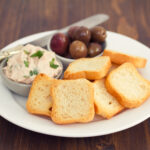 toasts with fish pate and olives on white plate